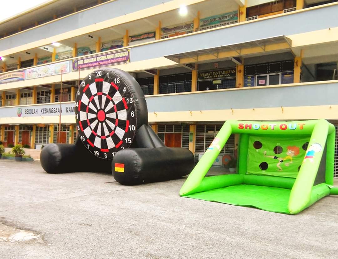 An inflatable football dartboard and shootout game set up in a school courtyard for charity activities.